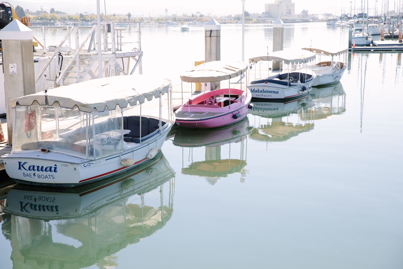 A Bae Boats electric boat on the Oakland Estuary with the Bay Area shoreline behind